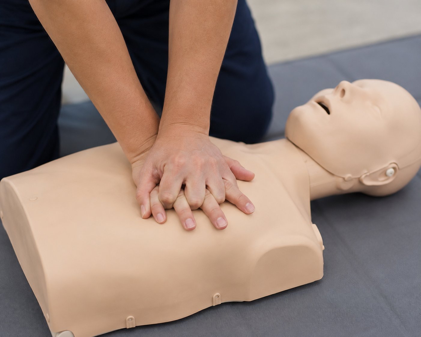 Hands performing CPR chest compressions on a mannequin training dummy during first aid instruction